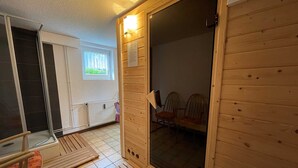 Ein Holzblock-Innenraum mit Schiebetür aus Glas, einem kleinen Fenster und einem Fliesenboden.