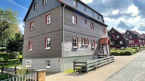 Ein zweistöckiges Gebäude mit einem geneigten Dach und roten Fensterrahmen.