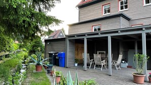 Ein überdachter Patio-Bereich mit Gartenmöbeln, Topfpflanzen und einem kleinen Garten mit Wasserspiel.