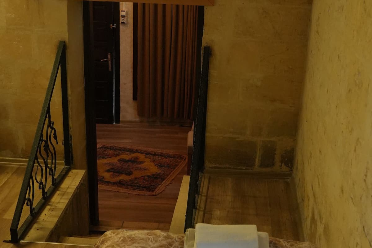 A bedroom with a bed, a wooden floor, a staircase, and a painting on the wall.