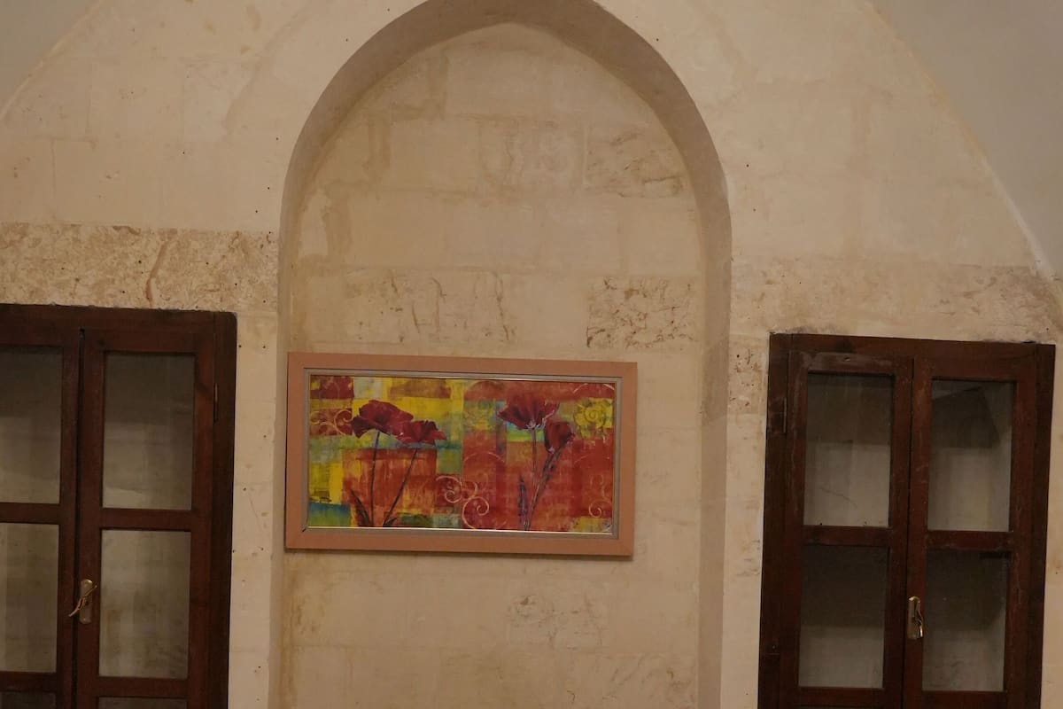 A bedroom with a large bed, a decorative painting, and two wooden cabinets.