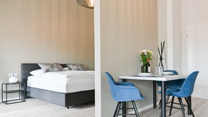 Un dormitorio moderno con una cama, una mesita de noche y una pequeña mesa con sillas.