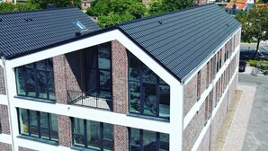 A modern building with large windows and a sloped roof. - Apartment 2 Teefabrik - Living at the Norder Tief (Lorup)