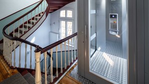 A staircase with wooden railings and a glass elevator door. - Apartment 4 Wohnen am Schloss - Living at Schloßplatz (Oldenburg)