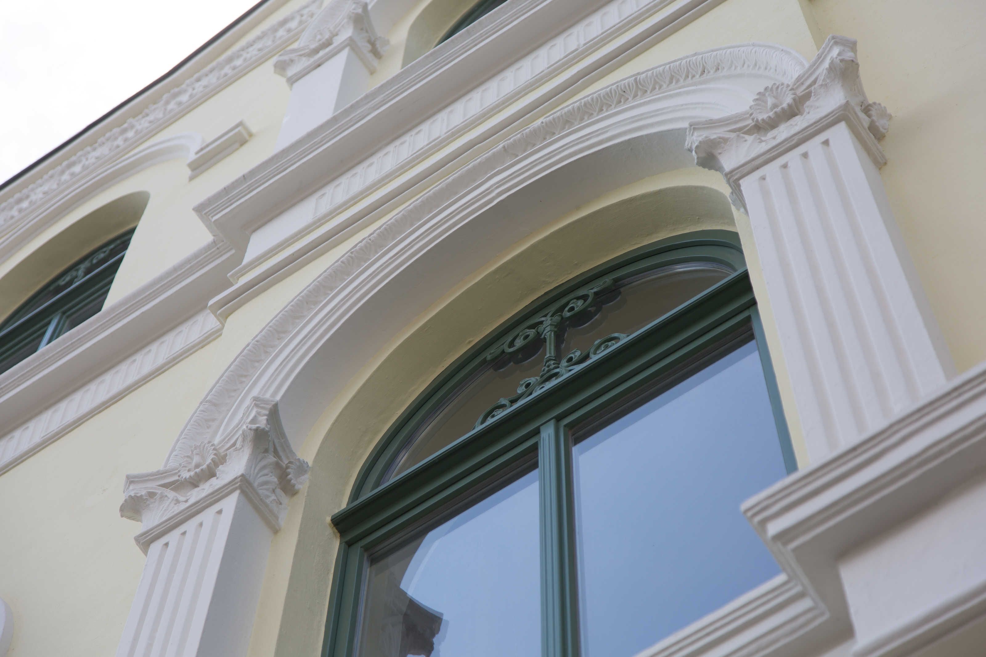 A building facade with ornate architectural details, including a large arched window and decorative moldings.