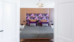 A modern bedroom with a large bed, a wooden floor, and a decorative wall panel. - Apartment 4 Wohnen am Schloss - Living at Schloßplatz (Oldenburg)