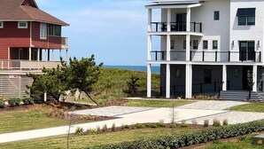Un immeuble moderne à deux étages, doté d’un balcon et offrant une vue sur l’océan.