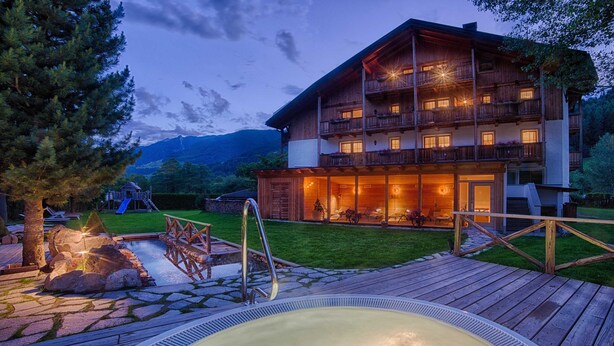 A wooden chalet with balconies, a hot tub, and a playground in a mountainous area. - Apartment "Löfflerblick A Möseler" with Mountain View, Wi-Fi & Jacuzzi (Steinhaus)