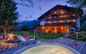 A wooden chalet with balconies, a hot tub, and a playground in a mountainous area. - Apartment "Löfflerblick A Wollbachspitz" with Mountain View, Wi-Fi, Sauna & Jacuzzi (Steinhaus)