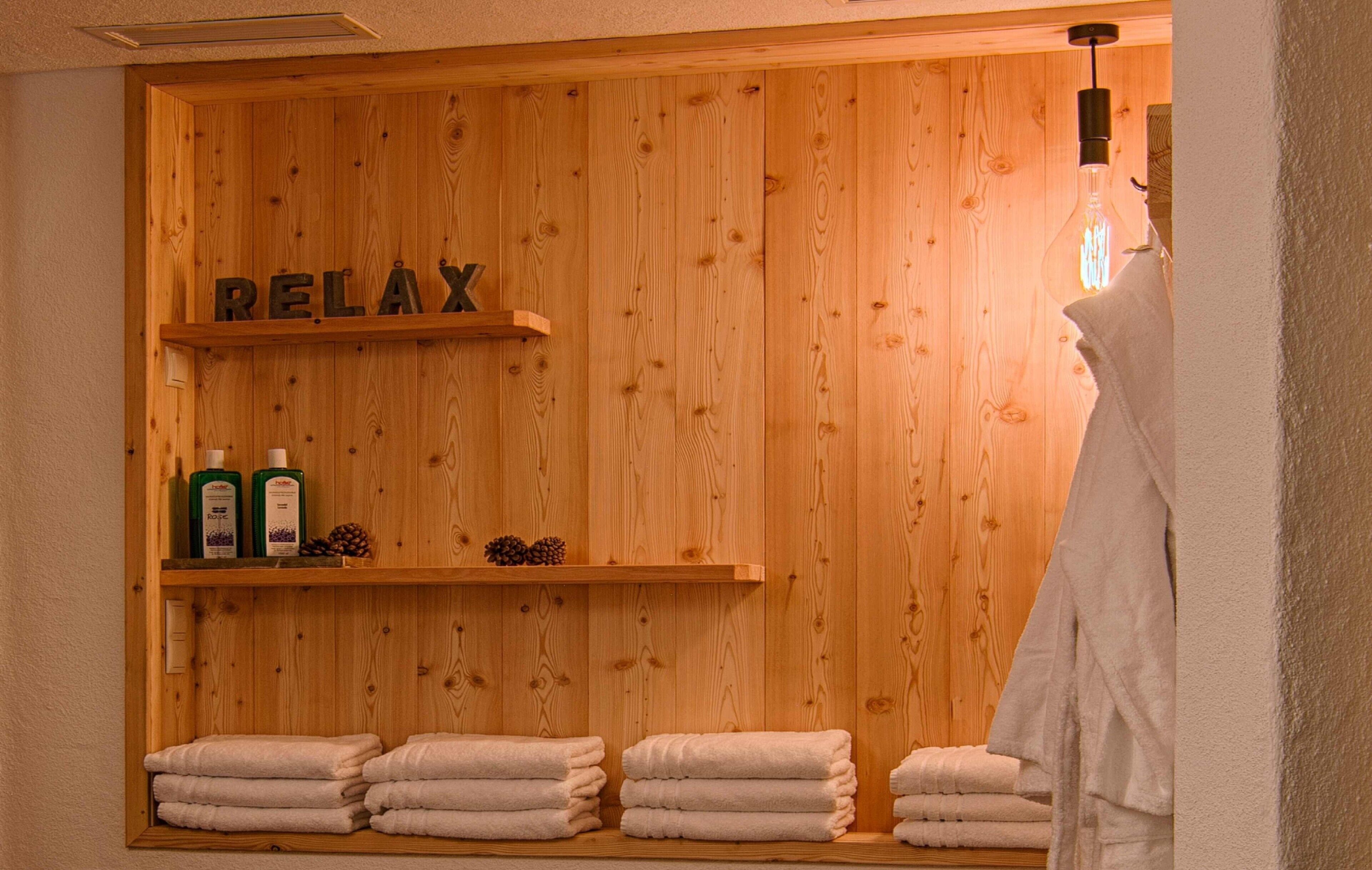 Eine Holzwand mit Regalen, auf denen Flaschen und Tannenzapfen stehen, und dem Wort 'RELAX' auf der Wand.