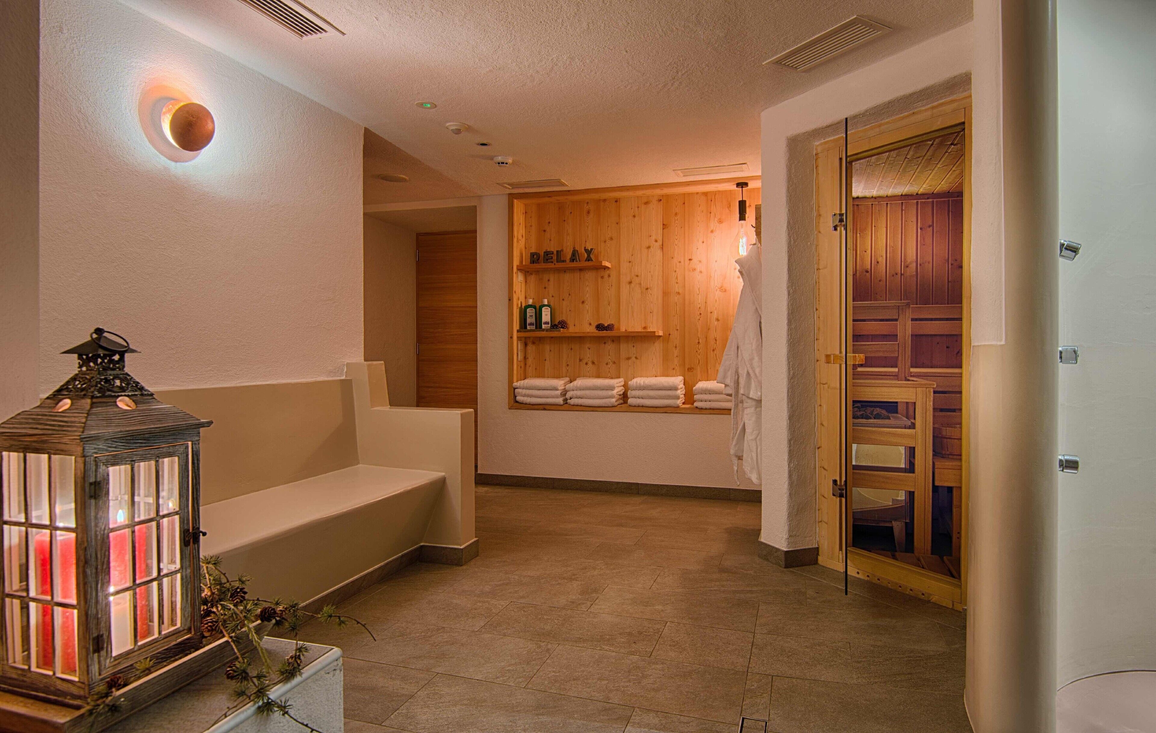Une salle de spa avec un mur en bois, un banc, une lanterne et une étagère avec des serviettes.