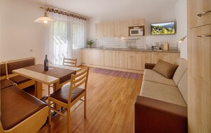 Une cuisine de taille réduite avec des meubles en bois, un coin repas comprenant une table et des chaises, et un canapé.