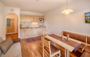 Une cuisine de taille réduite, dotée de meubles en bois, d’un four à micro-ondes et d’un luminaire suspendu.