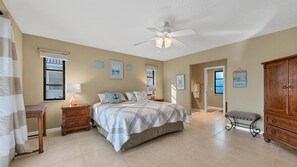A bedroom with a bed, two bedside tables, a ceiling fan, and a wardrobe.