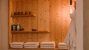 A wooden wall with shelves holding bottles and pine cones, and the word 'RELAX' on the wall.
