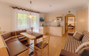 Un espace de vie compact comprenant un coin repas, une kitchenette et un canapé.