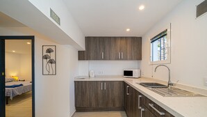 A modern kitchen with wooden cabinets, a microwave, a sink, and a window. - Casa De Mi Padre, La Fustera with Sea View, Wi-Fi and Air Conditioning (Benisa)