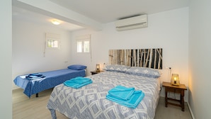 A bedroom with a bed, a smaller bed, two nightstands, an air conditioner, and two windows. - Casa De Mi Padre, La Fustera with Sea View, Wi-Fi and Air Conditioning (Benisa)