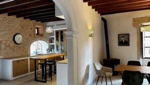 A modern kitchen with a stone wall, wooden ceiling beams, and a dining area with a table and chairs. - Holiday Home 'Numero Uno' with Sea View, Wi-Fi and Air Conditioning (Buger)