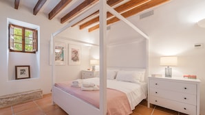 A bedroom with a four-poster bed, a bedside table with a lamp, a nightstand, and a wall-mounted air conditioner. - Holiday Home 'Numero Uno' with Sea View, Wi-Fi and Air Conditioning (Buger)