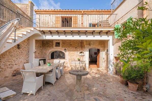 A courtyard with a stone table, wicker chairs, and potted plants.