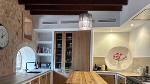 A modern kitchen with wooden cabinets, a central island with stools, a built-in oven, and a clock on the wall. - Holiday Home 'Numero Uno' with Sea View, Wi-Fi and Air Conditioning (Buger)