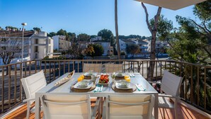 A balcony with a table set for breakfast, outdoor seating, and a view of the neighborhood. - La Encina Apartment with Mountain Views, Balcony, Shared Outdoor Area & Wi-Fi (Pto d'Alcudia)