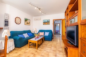 Una sala de estar con dos sofás, una mesa de centro, un televisor y un mueble de madera.