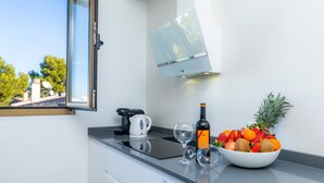 A kitchen with a built-in stove, a coffee maker, a bowl of fruit, and a wine bottle. - La Encina Apartment with Mountain Views, Balcony, Shared Outdoor Area & Wi-Fi (Pto d'Alcudia)