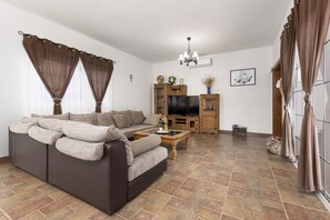 Una sala de estar con sofá, televisor, armarios de madera y una mesa de centro.