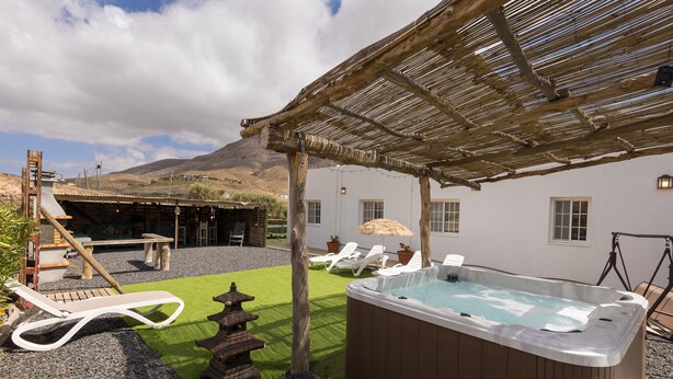 Un jacuzzi, sillas de descanso, una pérgola y vistas a la montaña.