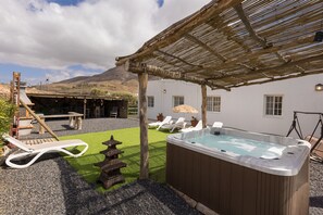 Una vasca idromassaggio, poltrone relax, una pergola e vista sulle montagne.