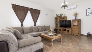 Una sala de estar con sofá, mesa de centro, mueble para televisor y candelabro.