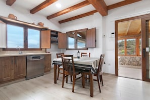 Una cocina con armarios de madera, lavavajillas y una mesa de comedor con sillas.