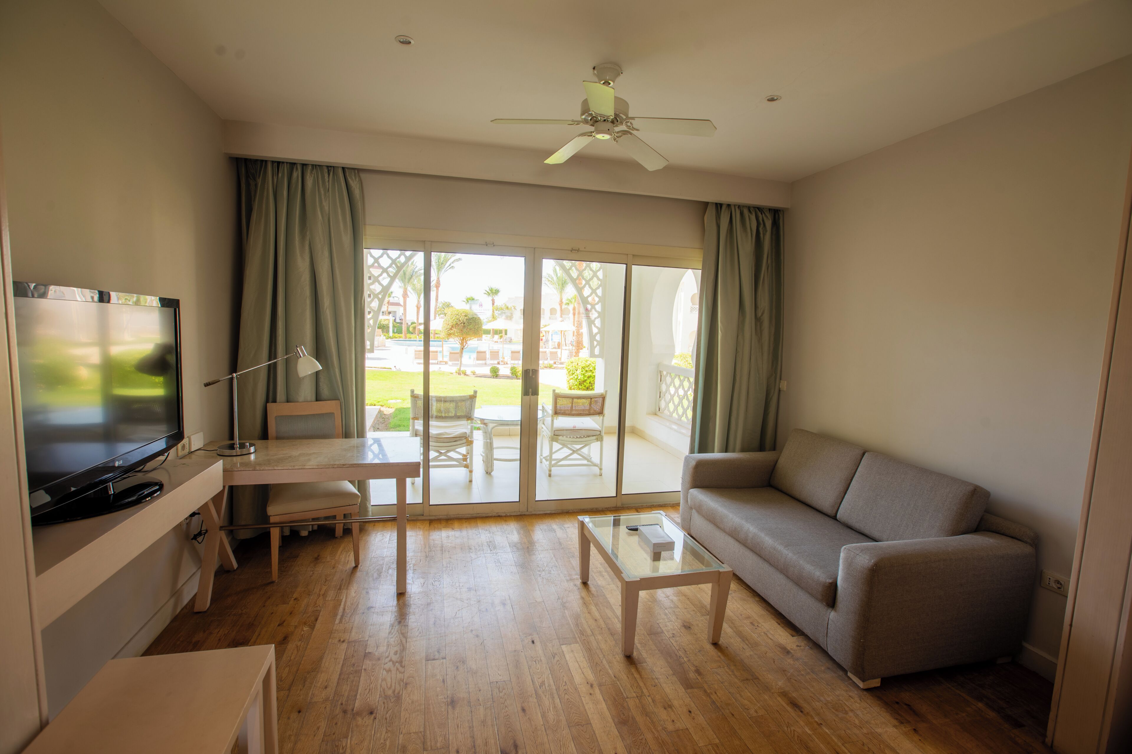 Ein Wohnzimmer mit Fernseher, Sofa, Couchtisch und Deckenventilator.