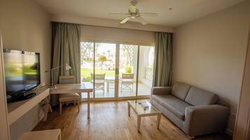 Ein Wohnzimmer mit Fernseher, Sofa, Couchtisch und Deckenventilator.