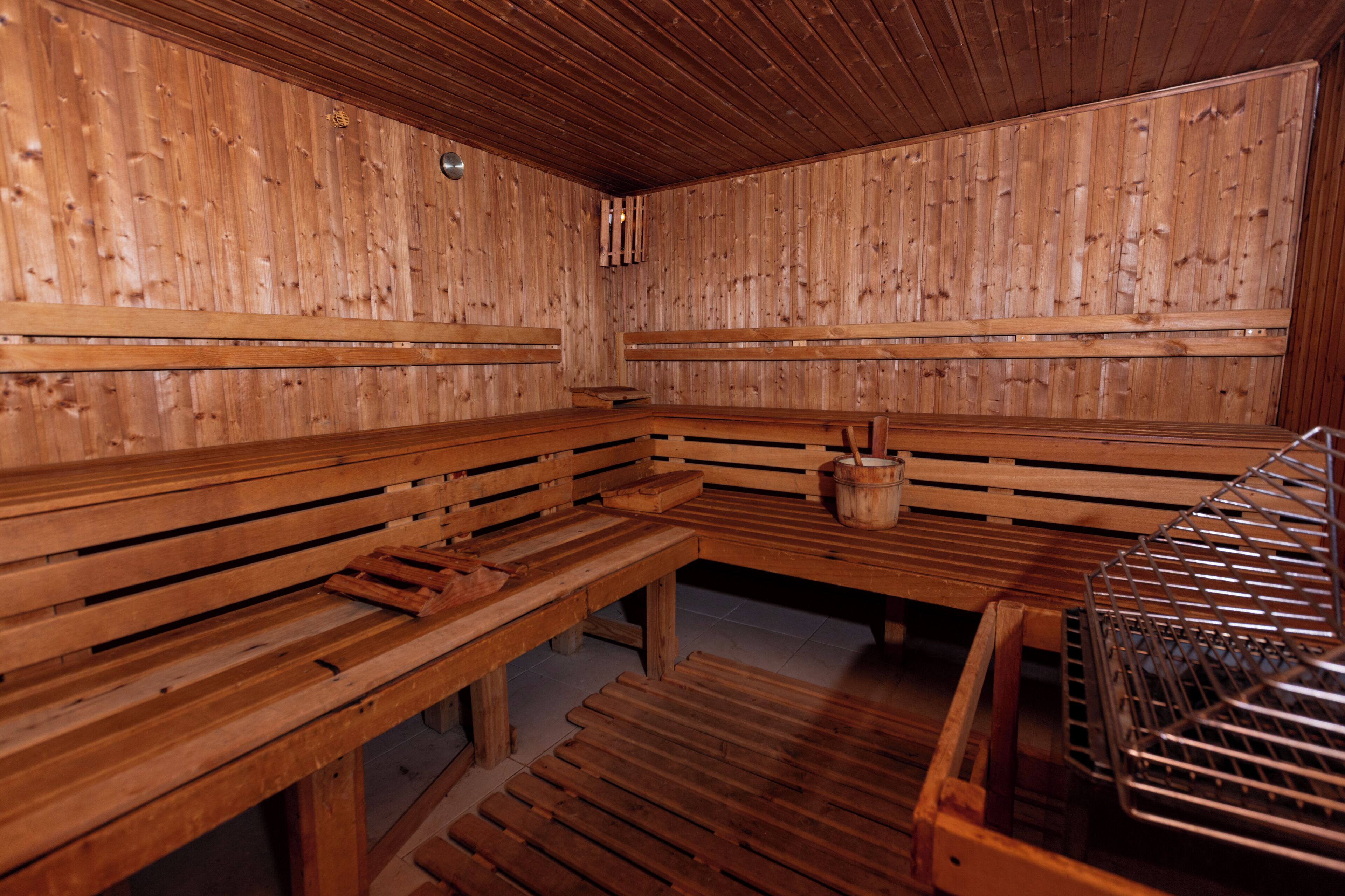 A wooden sauna with benches and a metal rack.