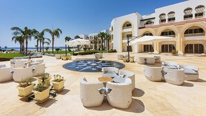 A resort courtyard with outdoor seating, a central fountain, and a view of the beach. - Old Palace Sahl Hasheseh (Sahl Hasheeh)