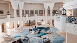 A spacious lobby with a central seating area, multiple levels with balconies, and a reception desk. - Old Palace Sahl Hasheseh (Sahl Hasheeh)
