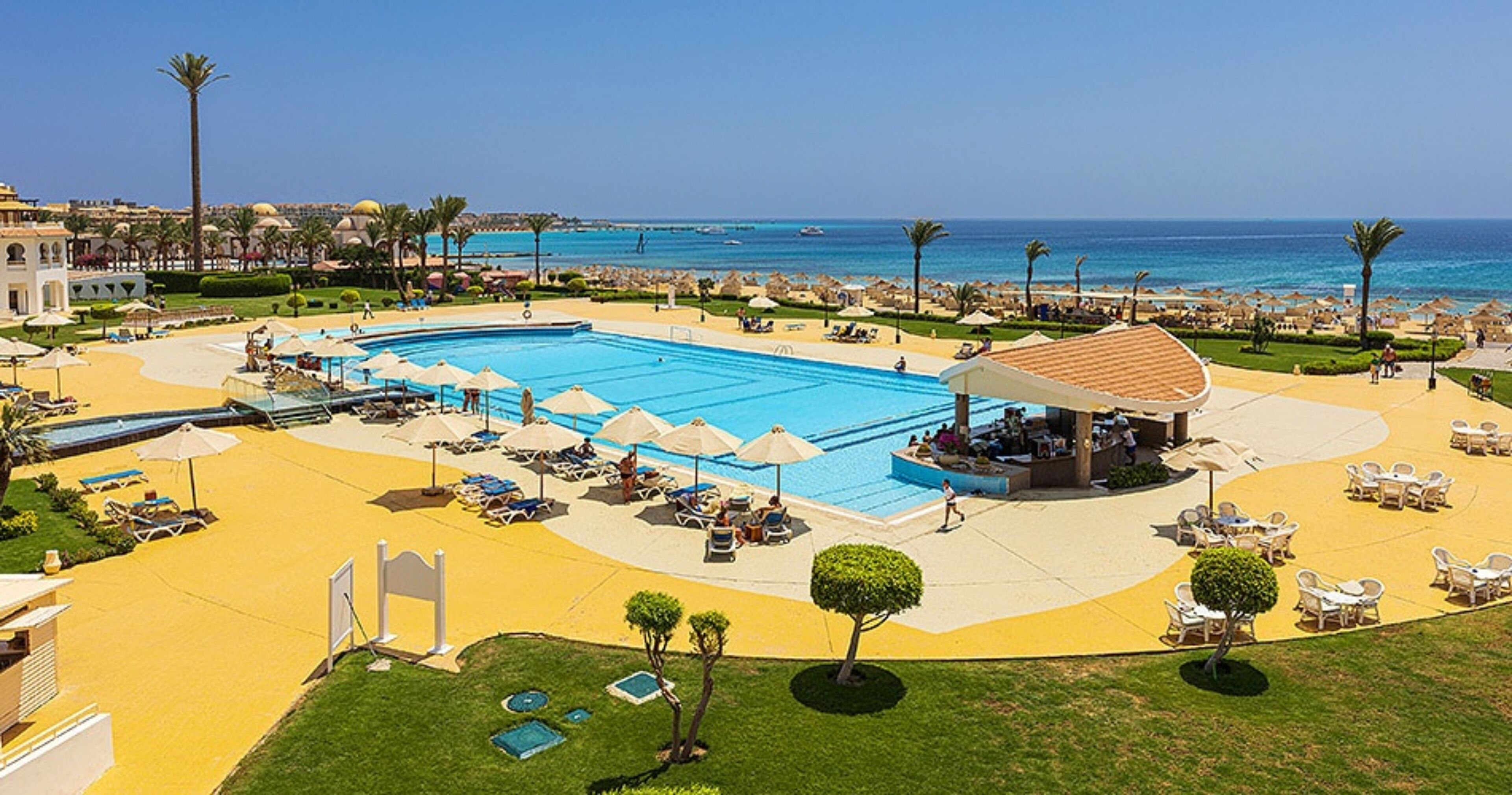 Un complexe hôtelier doté d’une grande piscine, de chaises longues et d’un espace plage.