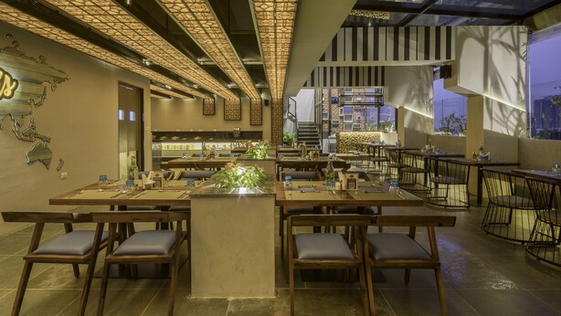 A modern restaurant with a central island, wooden tables, and chairs. - Le Foliage by TGI (Bengaluru)