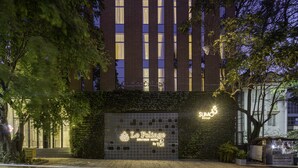 A modern hotel with a brick facade, illuminated windows, and a sign for 'Le Foliege Boutique Hotel by TGI'. - Le Foliage by TGI (Bengaluru)