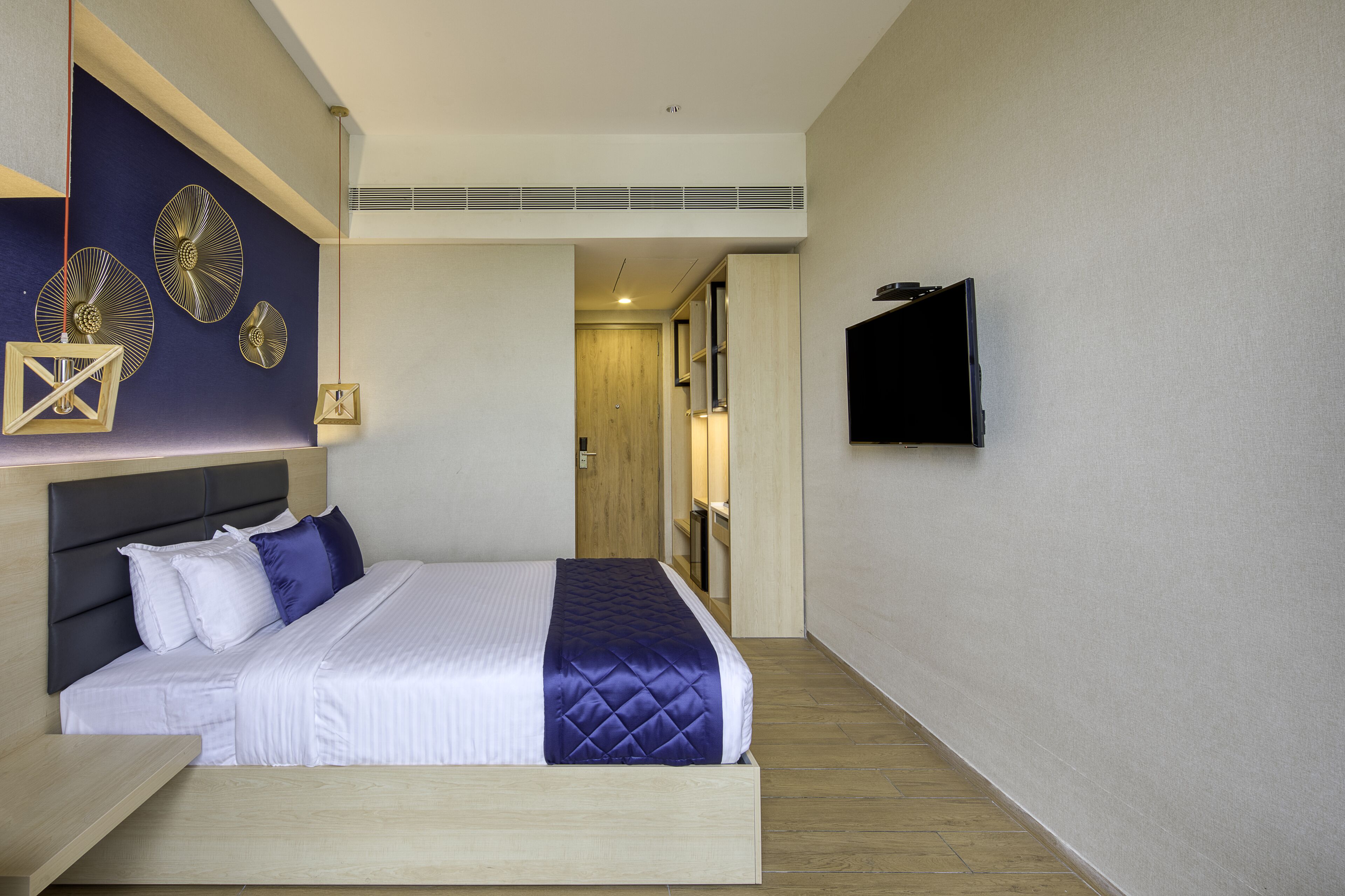 Ein modernes Hotelzimmer mit einem Bett, einem Fernseher und dekorativer Wandgestaltung.