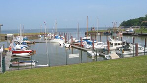 A marina with various boats docked, a grassy area in the foreground, and a clear sky. - Dirks Ferienhaus Fleute - Holiday home Fleute (Varel)