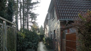 A narrow brick pathway leading to a building with a tiled roof. - Dirks Ferienhaus Fleute - Holiday home Fleute (Varel)