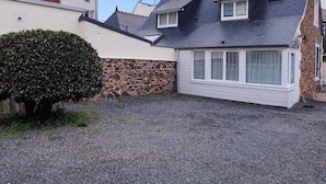 A residential property with a stone wall, a gravel driveway, and a small garden.