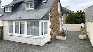 A two-story house with a sloped roof, a small balcony, and a gravel driveway.