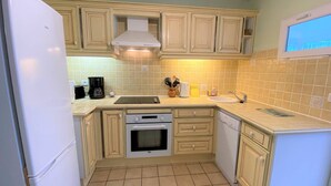 A compact kitchen with a refrigerator, oven, dishwasher, and a small sink.
