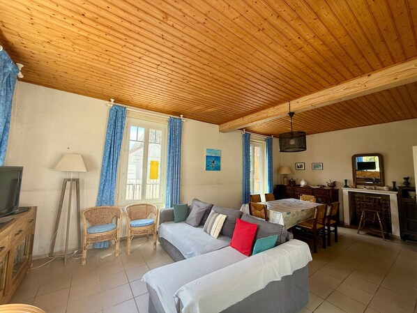 Un salon avec un plafond en bois, un canapé, une table à manger et un téléviseur.