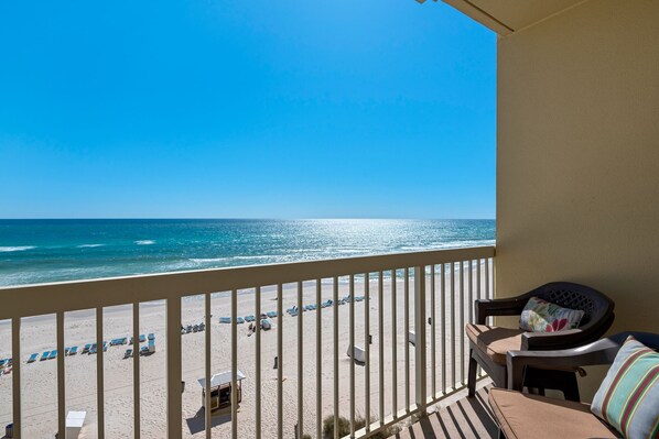 A balcony with a view of the beach and ocean.